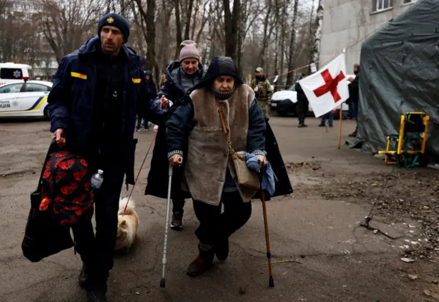 Emergency service member helps Vera, 67, as walks after she was evacuated from Irpin town, as Russia"s attack on Ukraine continues, on the outskirts of Kyiv, Ukraine March 30, 2022.