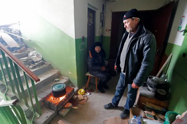 Residents cook in the stairwell of an apartment building, 28 March