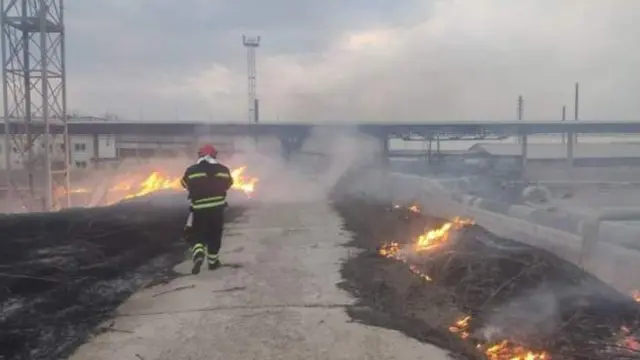 A firefighter walks past fires at an oil depot