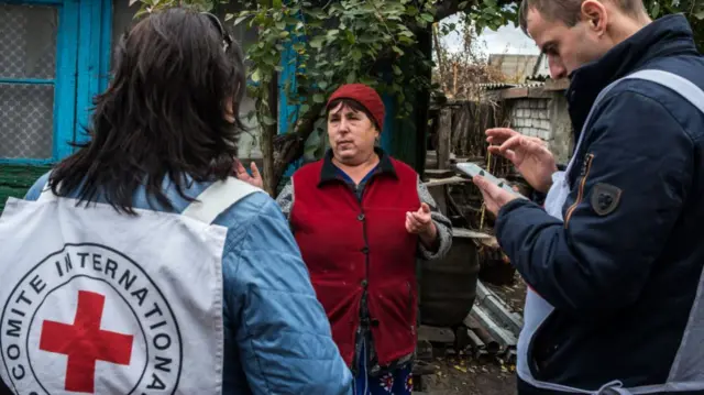 An International Committee of the Red Cross representative talks to a Ukrainian woman in her village in October 2018 in Luhansk, Ukraine