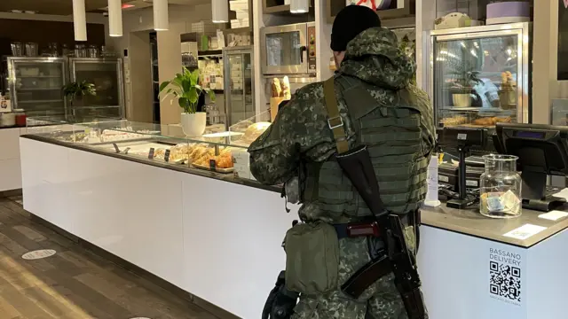 A Ukrainian soldier dressed in military fatigues examines the counter filled with pastries in a cafe in Kyiv