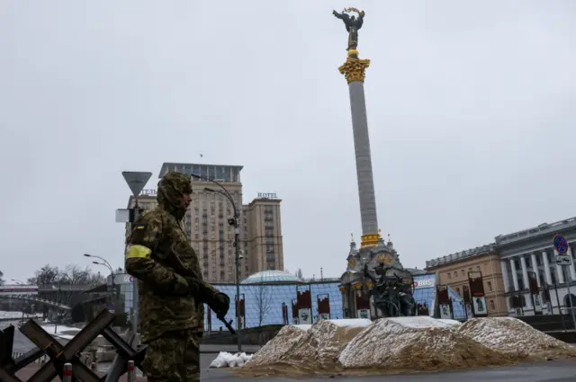 A soldier stands guard in front of bars and sand barriers at the Independence Square