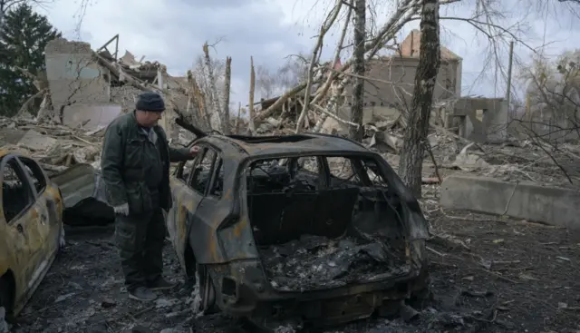 A man inspects a car destroyed in Byshiv in the Kyiv region of Ukraine