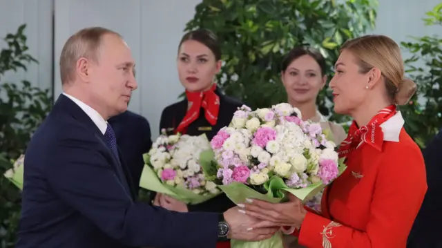 Putin exchanges flowers with a woman from Aeroflot flight crew