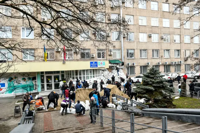 People fill the bags with sand outside the Emergency Care Hospital to reinforce the building as Ukraine has been under attack from Russia since Thursday, February 24, Zaporizhzhia, southeastern Ukraine