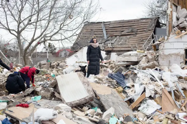 A woman stands amid the rubble in Markhalivka, Ukraine on 5 March