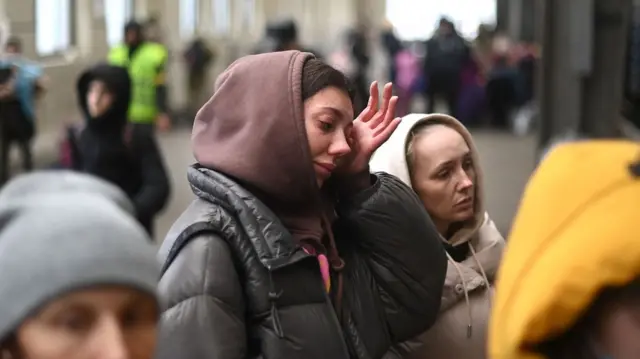 A woman cries as she boards a train to Poland