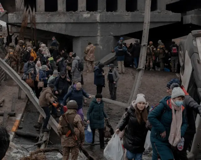 People moving off a collapsed bridge in Irpin, Kyiv