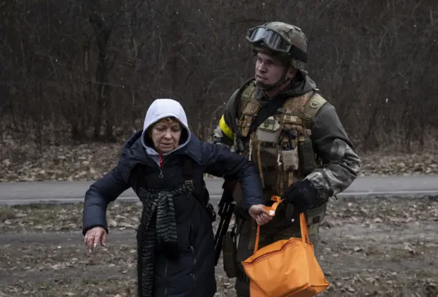 A Ukrainian soldier helps a woman