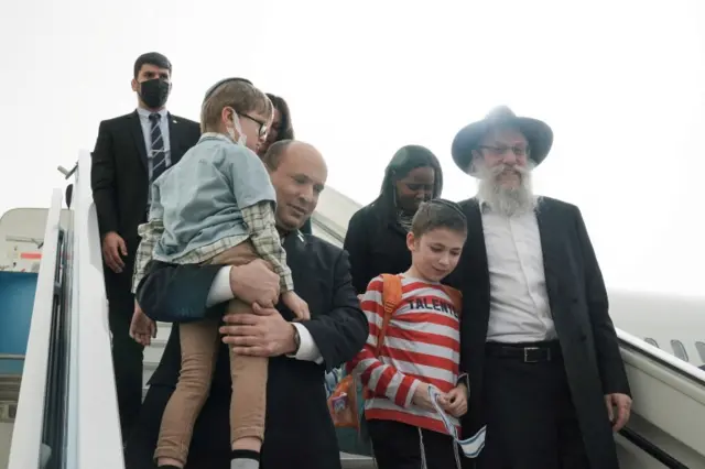 Israeli Prime Minister Naftali Bennett carries a Jewish boy from a plane bringing some 90 children from a Jewish orphanage in Zhytomyr