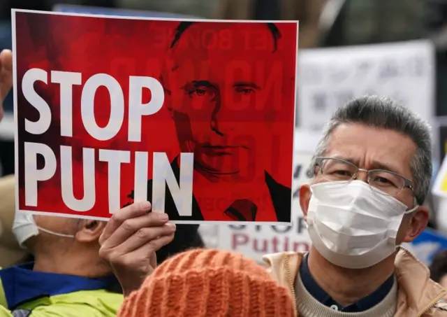 Protester in Tokyo holds sign saying 'stop Putin'