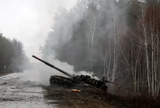 Smoke rises from a Russian tank destroyed by the Ukrainian forces on the side of a road in Lugansk region on February 26, 2022.