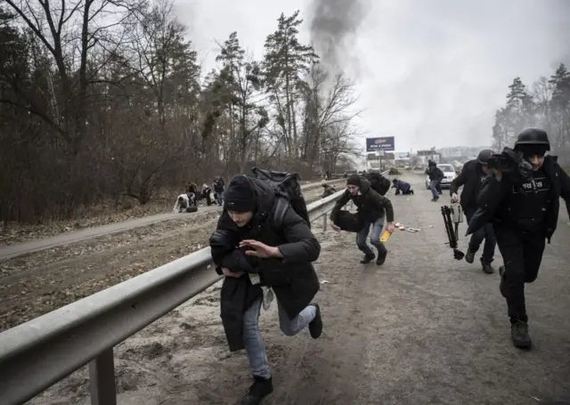 People crouch down as they run from a blast in Irpin, on the outskirts of Kyiv