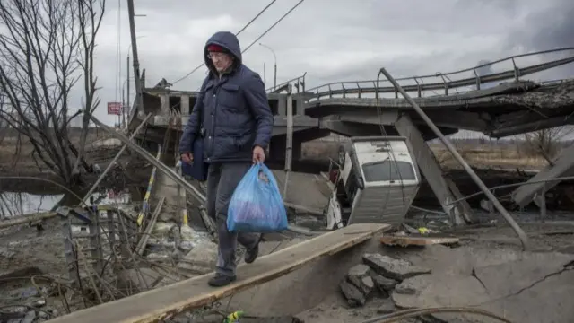 Civilians cross a damaged bridge as they attempt to leave Irpin, near Kyiv