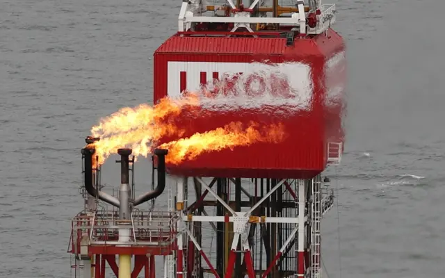 A gas torch is seen next to the Lukoil company sign at the Filanovskogo oil platform in the Caspian Sea, Russia, on 16 October 2018