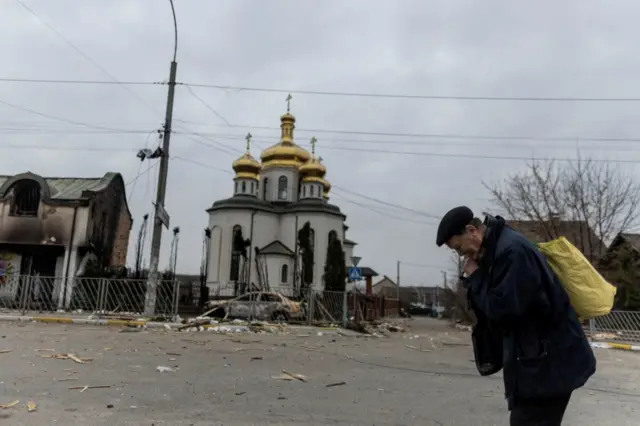 A man evacuates from Irpin, on the only escape route used by locals after days of heavy shelling