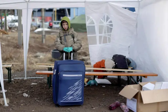 A child stands with a suitcase as refugees from Ukraine cross the Ukrainian-Slovakian border in Vysne Nemecke, Slovakia, on 3 March 2022