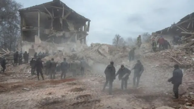 People remove debris at the site of a military base building in Ukraine's Sumy region