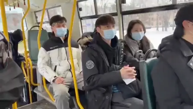 Civilians, including foreign students, sit in an evacuation bus