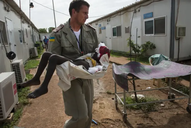 Ukrainian UN policeman carrying wounded child in South Sudan in 2014