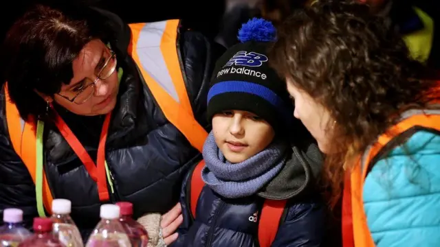 Customs officials greet Hassan and give him water and food at the Slovakia border