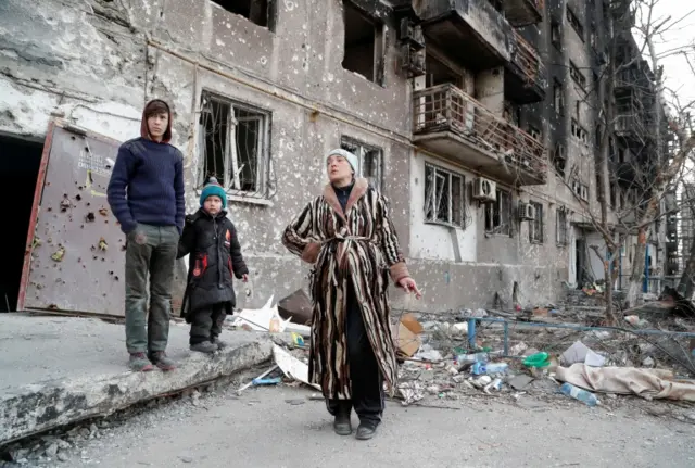 Residents by damaged apartments in Mariupol