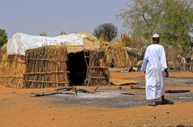 A Sudanese man walks past a burnt shack following violence in the village of al-Twail Saadoun, 85 kilometres south of Nyala town, the capital of South Darfur, on February 2, 2021