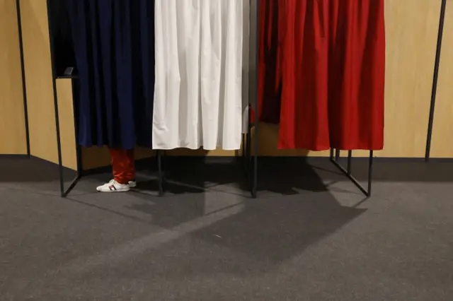 A voter stands in a polling booth, in the colours of the French flag, to vote in the first round of the 2022 French presidential election at a polling station in Le Touquet-Paris-Plage, France, on 10 April 2022