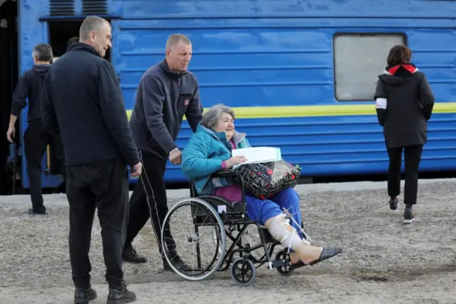 A woman sits on a wheelchair as medical workers assist evacuated and wounded people that arrived from Bakhmut and Slovyansk for treatment, amid Russia"s invasion of Ukraine, in Lviv,