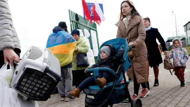 Ukrainian refugees walk after crossing the Ukraine-Poland border, amid the Russian invasion of Ukraine, in Medyka, Poland, April 10, 2022