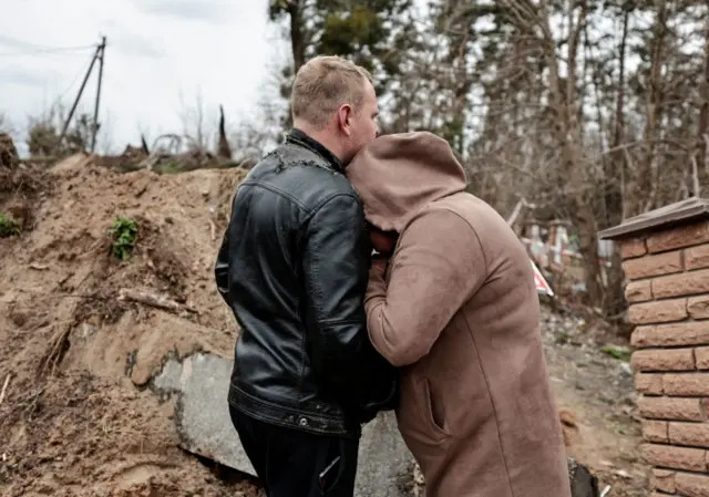 A mother reacts as she waits for police members to exhume the body of her dead son from a well at a fuel station in Buzov