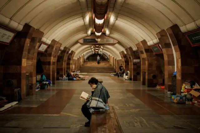 A woman reads a book as residents find shelter from shelling in a metro station, amid Russia"s attack on Ukraine, in Kharkiv, Ukraine, April 11, 2022.