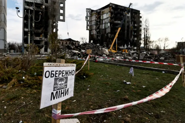 A landmine warning sign in front of shelled buildings in Borodyanka, near Kyiv