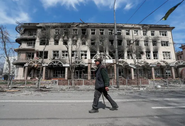 A man walks past a destroyed building in Mariupol