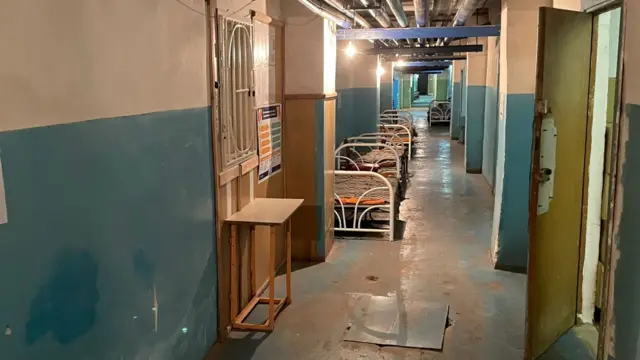 Hospital beds line the corridor of the basement