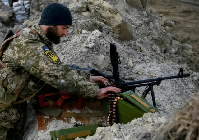 A Ukrainian serviceman checks his machine gun near Kyiv last month