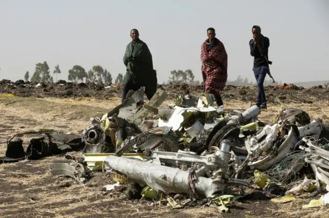 Ethiopian police officers walk past the debris of the Ethiopian Airlines Flight ET 302 plane crash