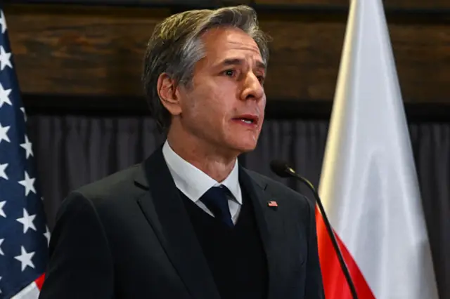 Anthony Blinken speaking in front of a US flag