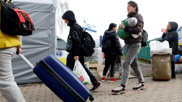 Ukrainian refugees walk after crossing the Ukraine-Poland border, in Medyka.