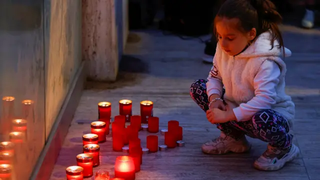 A child crouches next to candles during a vigil for Ukrainians in Malta