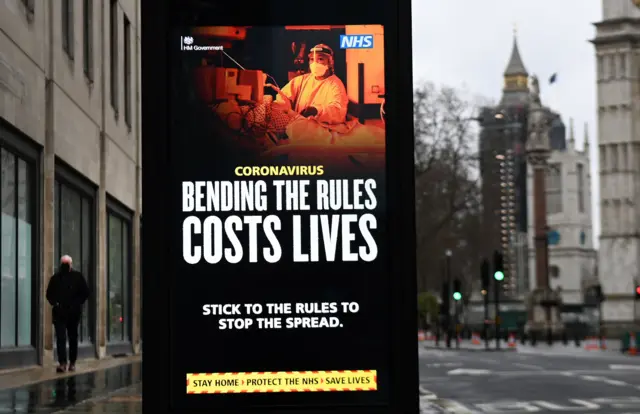 A poster reading "Bending the rules costs lives" near the Houses of Parliament in January 2021