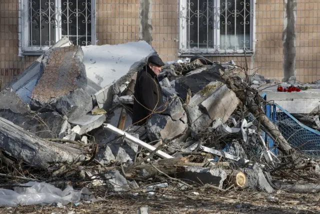 A man walks through the debris of a building in Donetsk