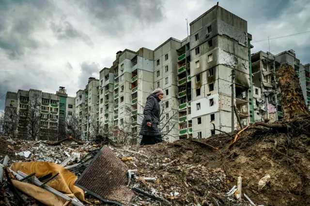 A woman walks past a badly damaged building in Chernihiv