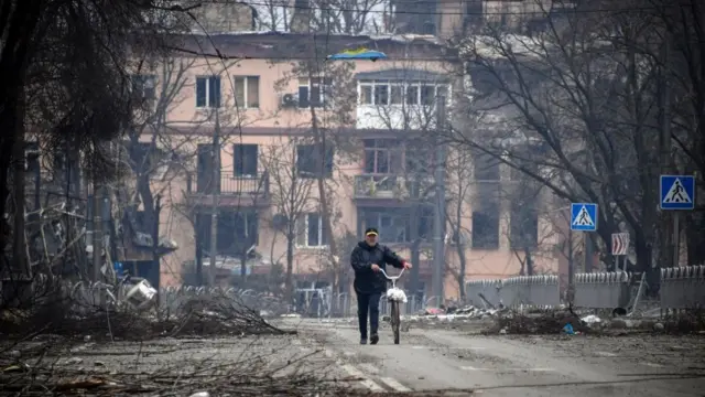 A man walks with a bicycle in downtown Mariupol on April 12, 2022, as Russian troops intensify a campaign to take the strategic port city