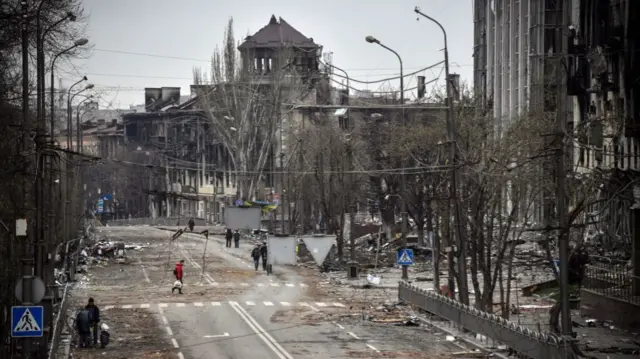 People walk down an avenue of Mariupol on April 12, 2022