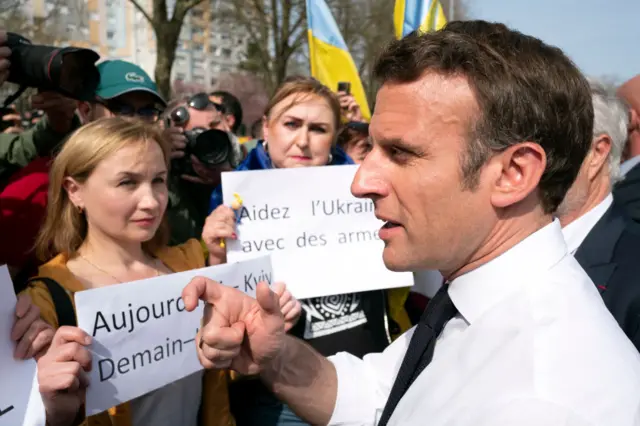 Emmanuel Macron speaks with women holding anti-Ukraine war placards during his first campaign appearance in March 2022 in Dijon, France