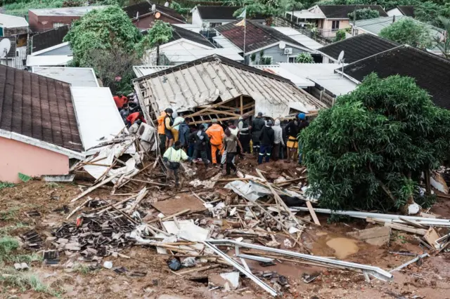 People dig for persons believed to be trapped at a house in Bonela township collapsed following heavy rains and winds in Durban, on April 12, 2022