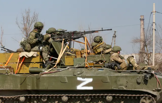 Service members of pro-Russian troops on an armoured vehicle with a symbol "Z" painted on its side