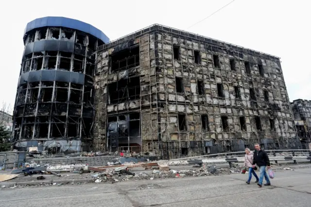 People walk past damaged building in Mariupol on 14 April 2022