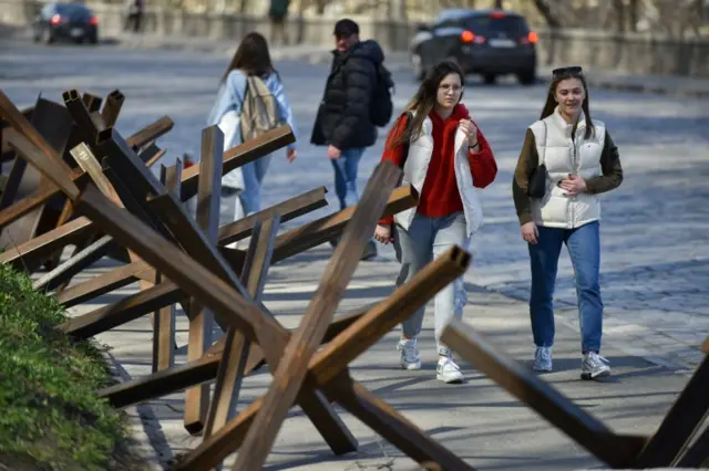 People pass the anti-tank hedgehogs in downtown Kyiv, Ukraine, 15 April 2022